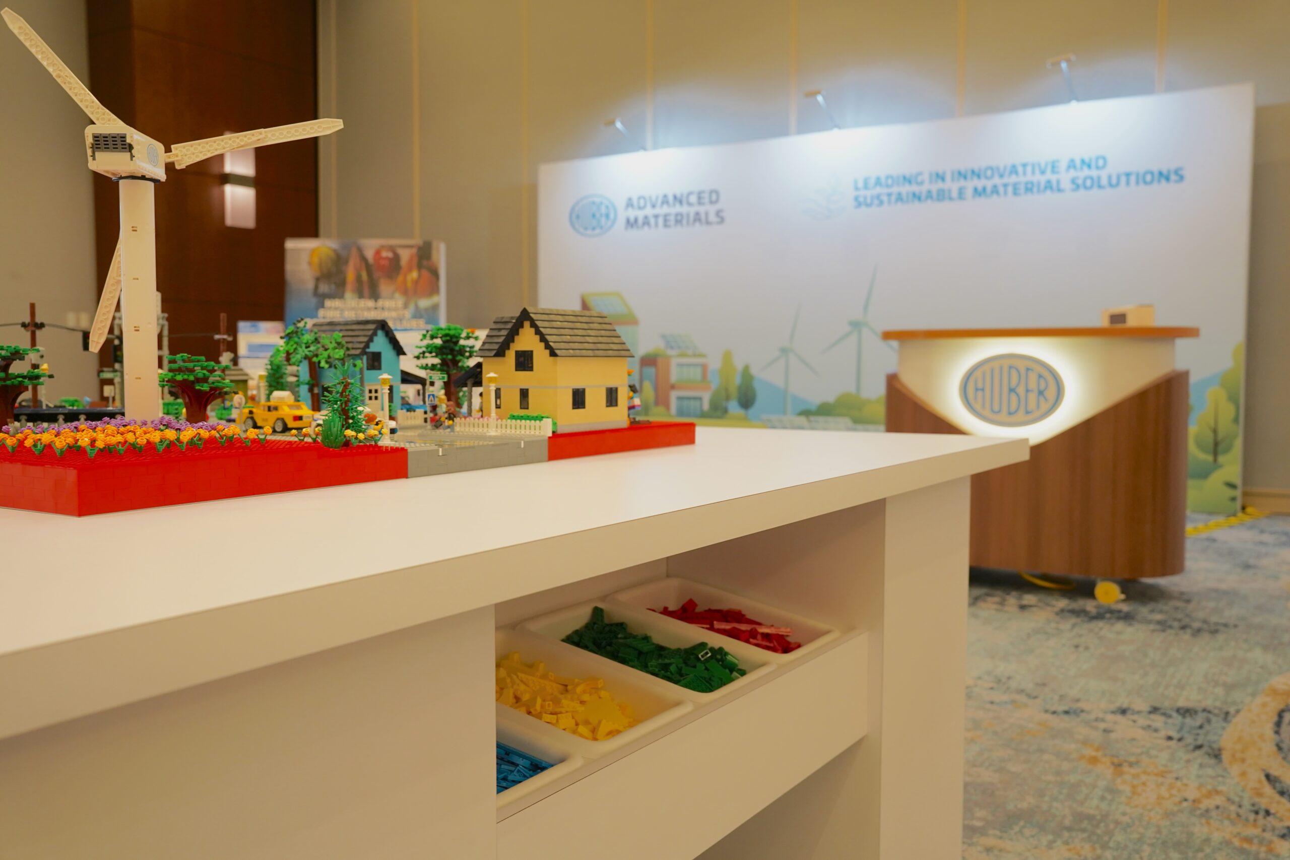 Huber LEGO city display shown on a table with color-sorted bulk LEGO brick bins below for attendee interaction