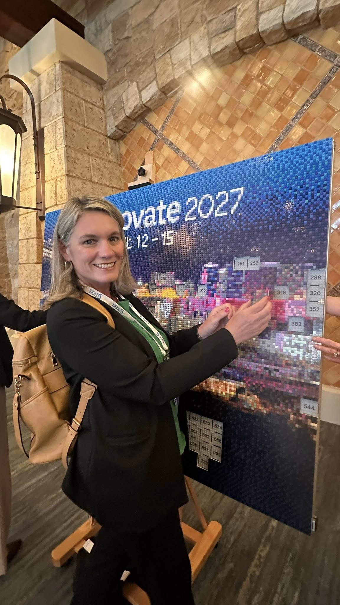 Attendee posing with the completed SAS Innovate 2027 LEGO mosaic reveal