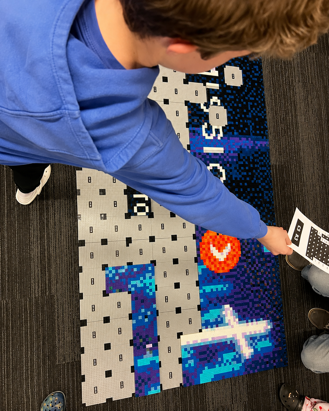 A participant placing a completed section into the growing Mission Forward LEGO mosaic